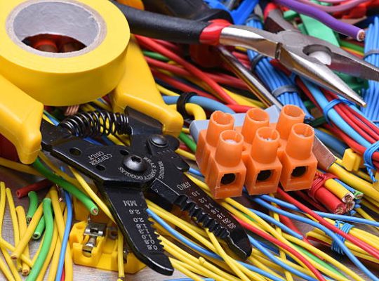Electrical tools and cables used in electrical installations on grey metal background